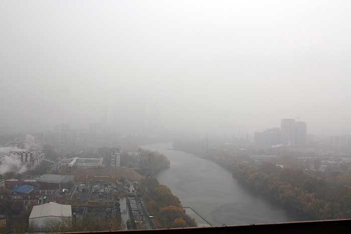 Башни делового центра «Москва-Сити» утопают в тумане, и видны только река и близлежащая промзона